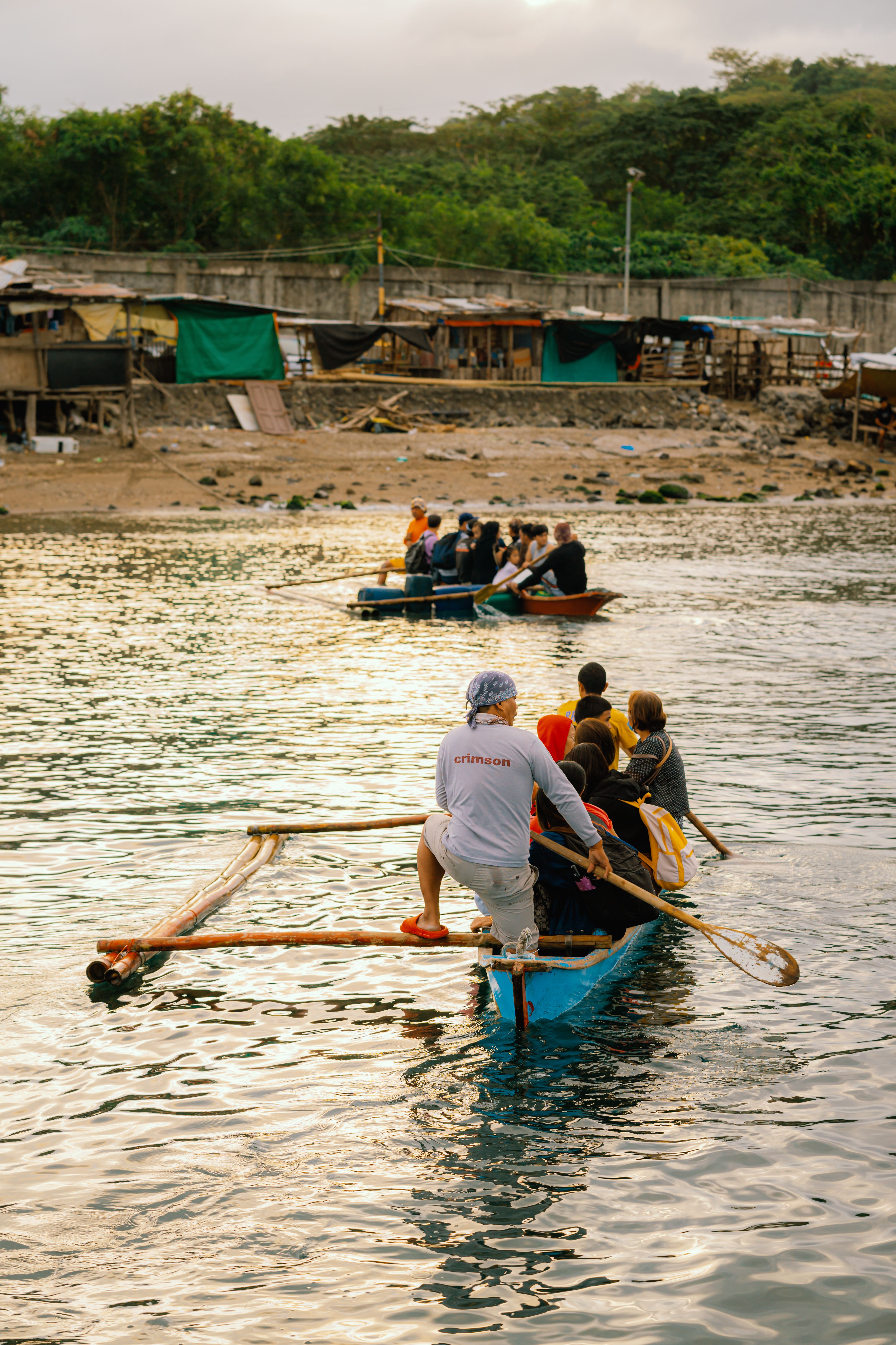 Group Paddle Boating Near Rustic Beachfront · Free Stock Photo