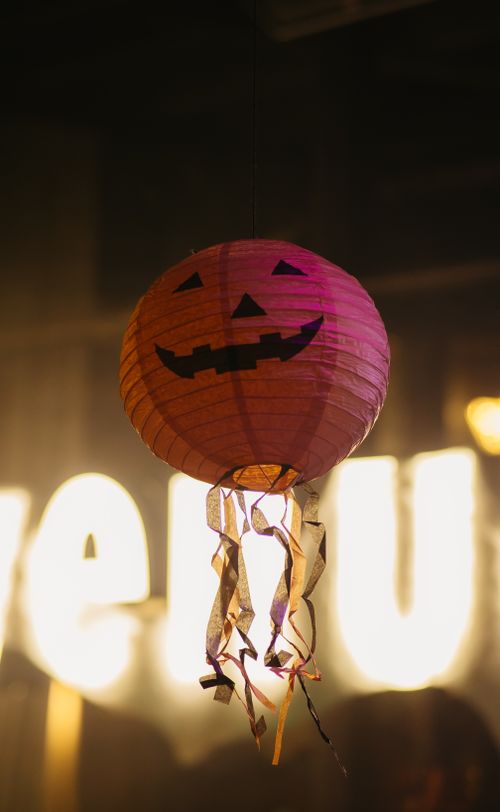Free A spooky Halloween lantern with a pumpkin face and hanging ribbons indoors. Stock Photo