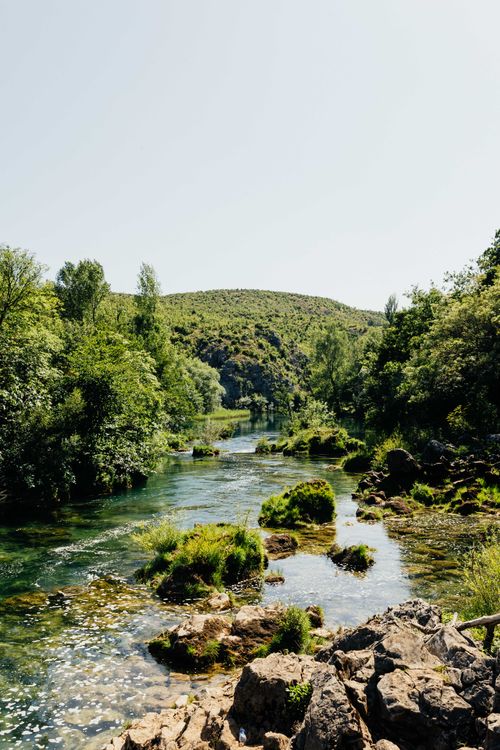 Free A tranquil river meanders through a lush, green landscape, evoking a sense of peace. Stock Photo