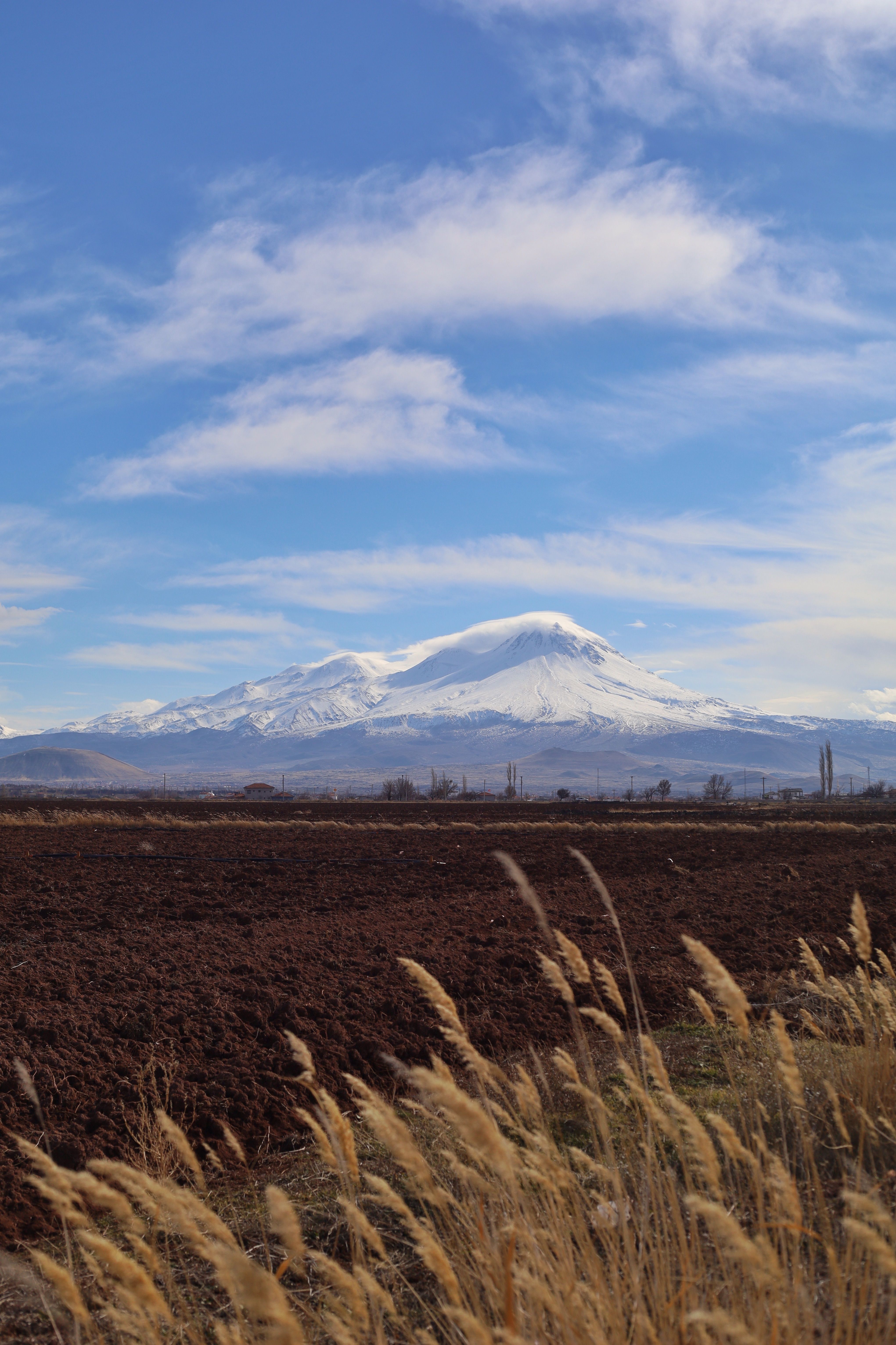 Scenic view of snow-capped Mount Hasan with a foreground of fields in Aksaray, Türkiye.