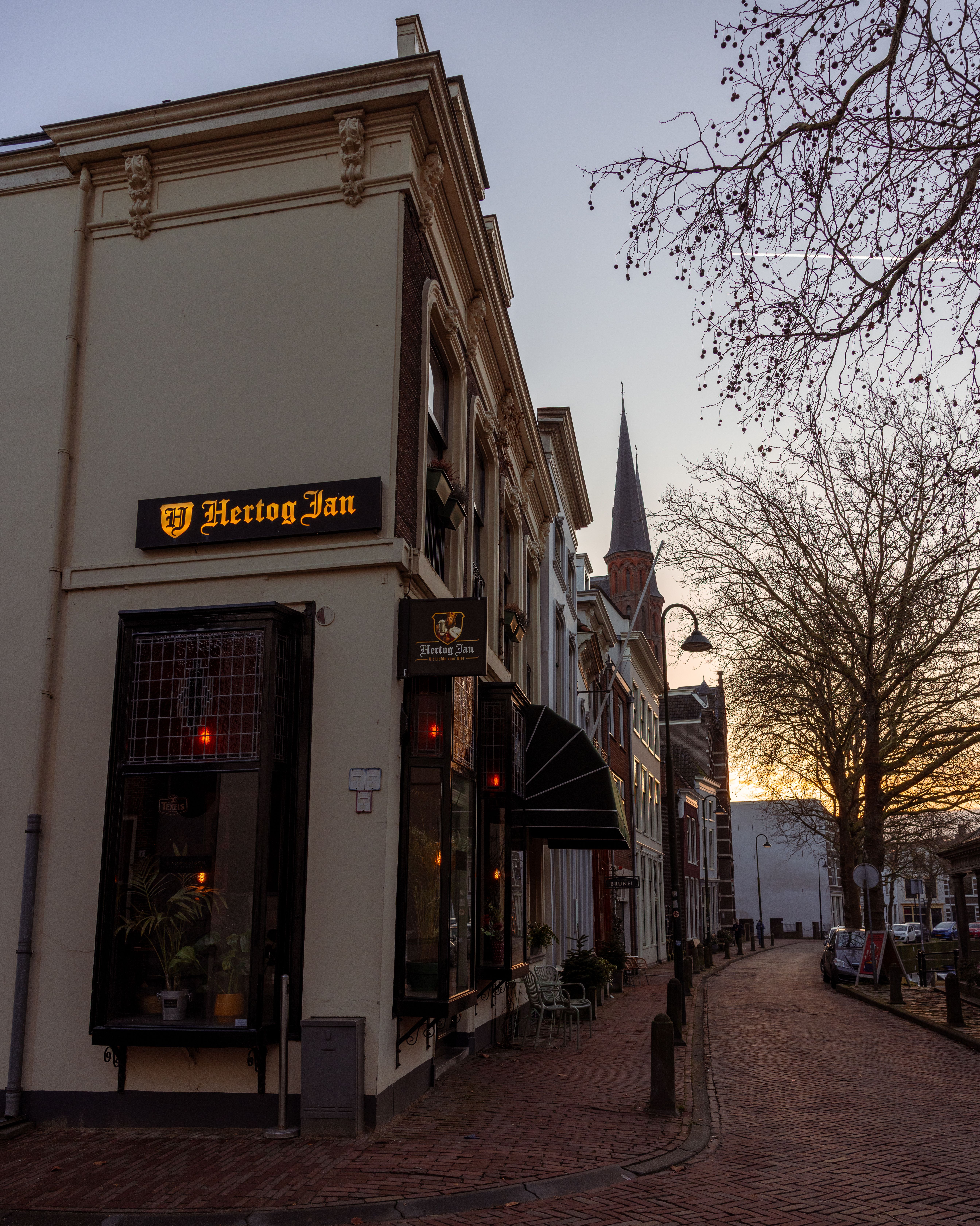 Serene streetscape in Gouda at sunset with quaint architecture and street lanterns.