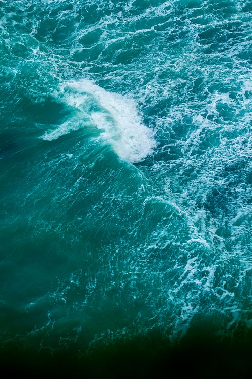 Free Vibrant, dynamic aerial shot of turquoise ocean waves crashing with white foam. Stock Photo