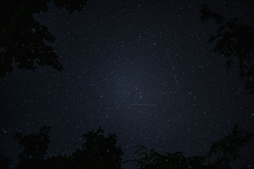 Free A mesmerizing night sky filled with stars and visible meteor trails. Stock Photo