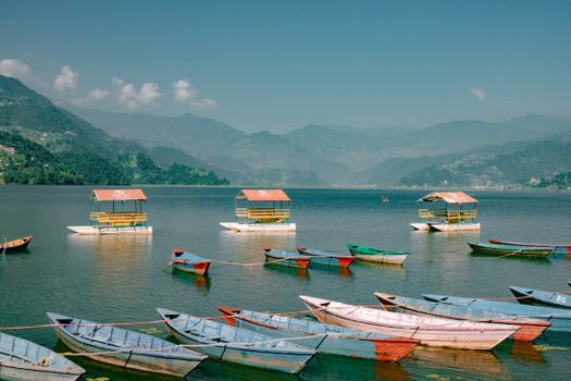 Vibrant boats floating on serene Phewa Lake against a backdrop of lush mountains.
