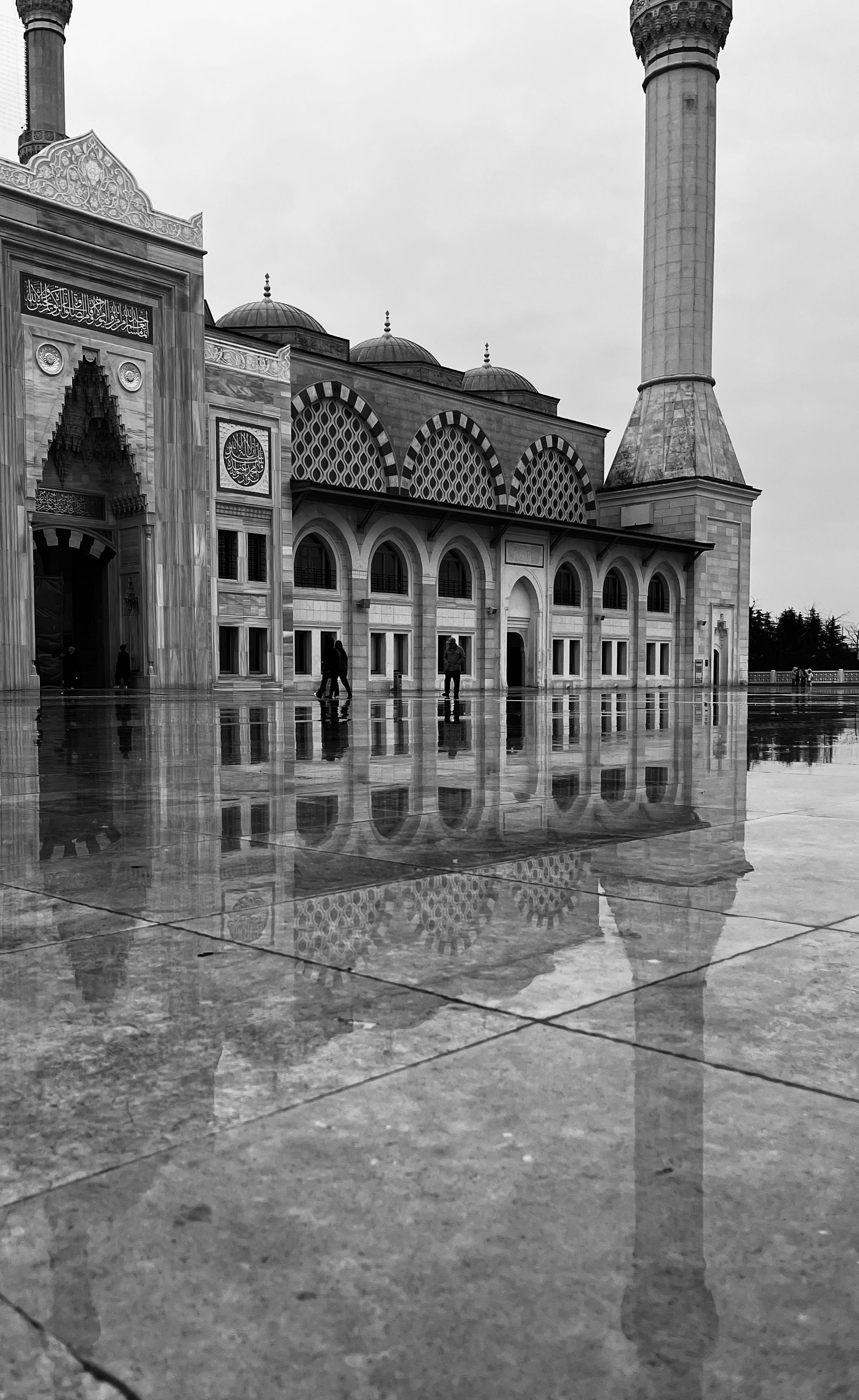 Silhouette reflection of grand mosque with minarets on wet ground in monochrome tone.