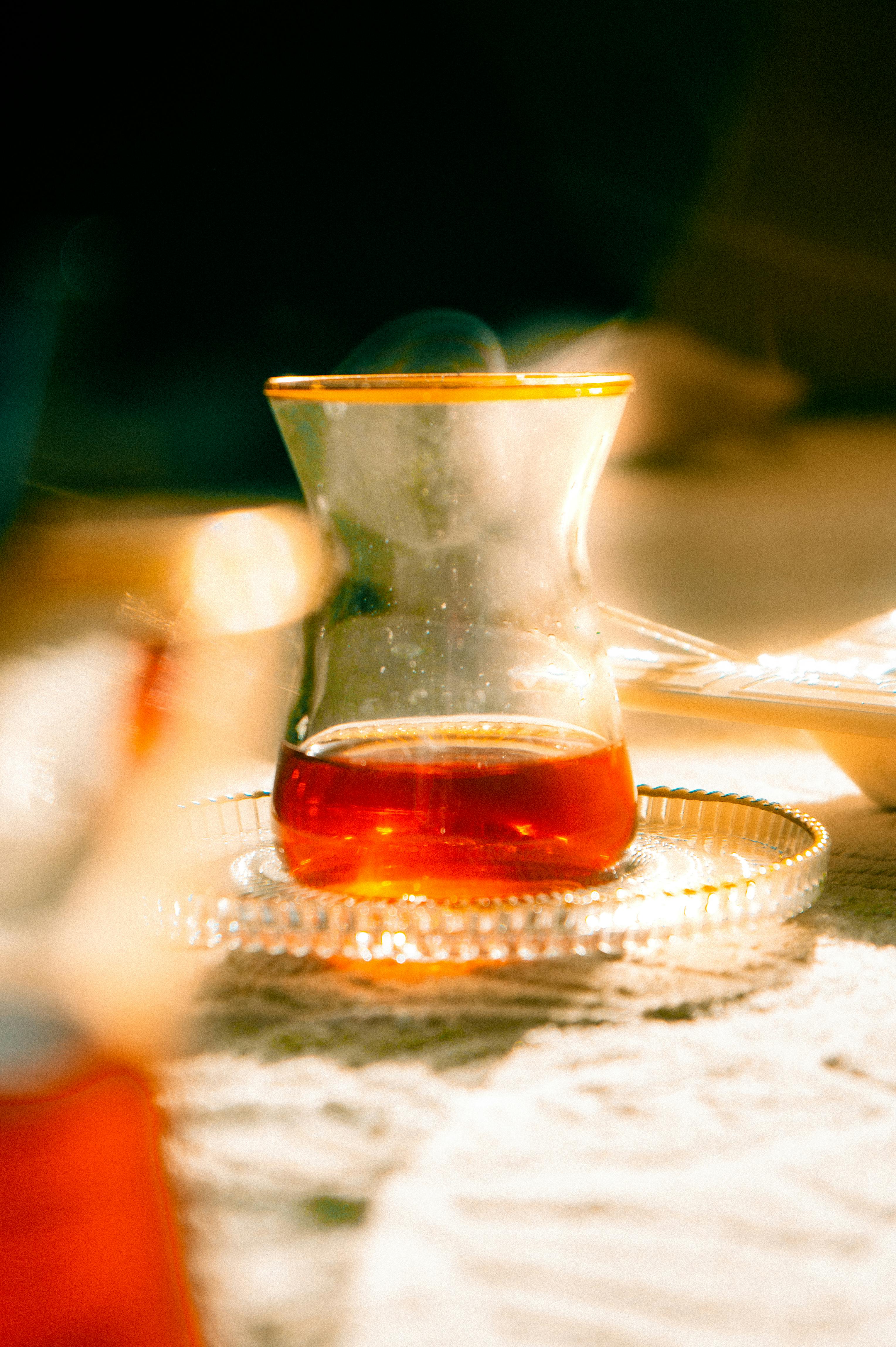 Gratis Elegante primo piano di un tè turco in un bicchiere decorativo che brilla sotto la calda luce del sole. Foto a disposizione