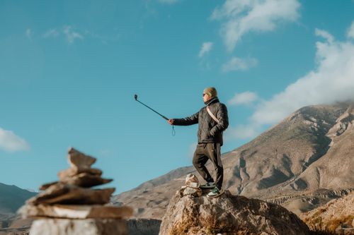 Free A man captures a selfie with a beautiful mountain backdrop on a sunny day. Stock Photo