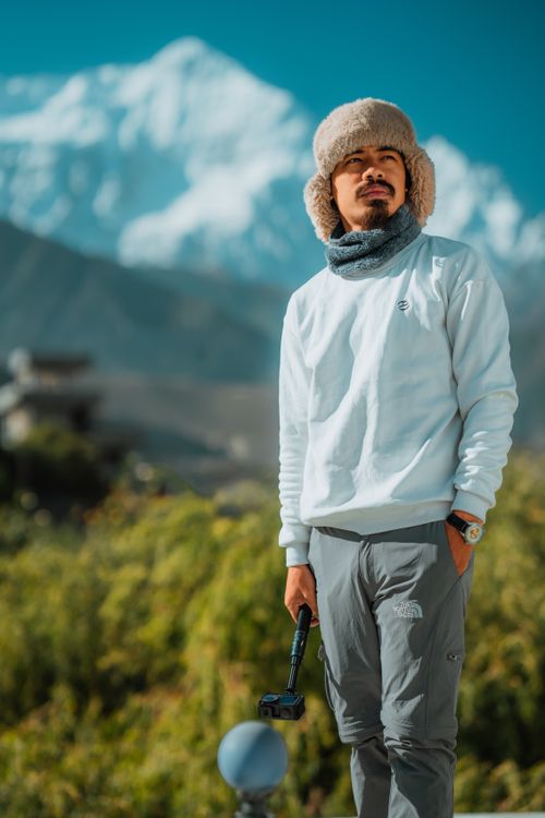 Free A man in winter attire stands outdoors with a mountain backdrop, exuding an adventurous spirit. Stock Photo