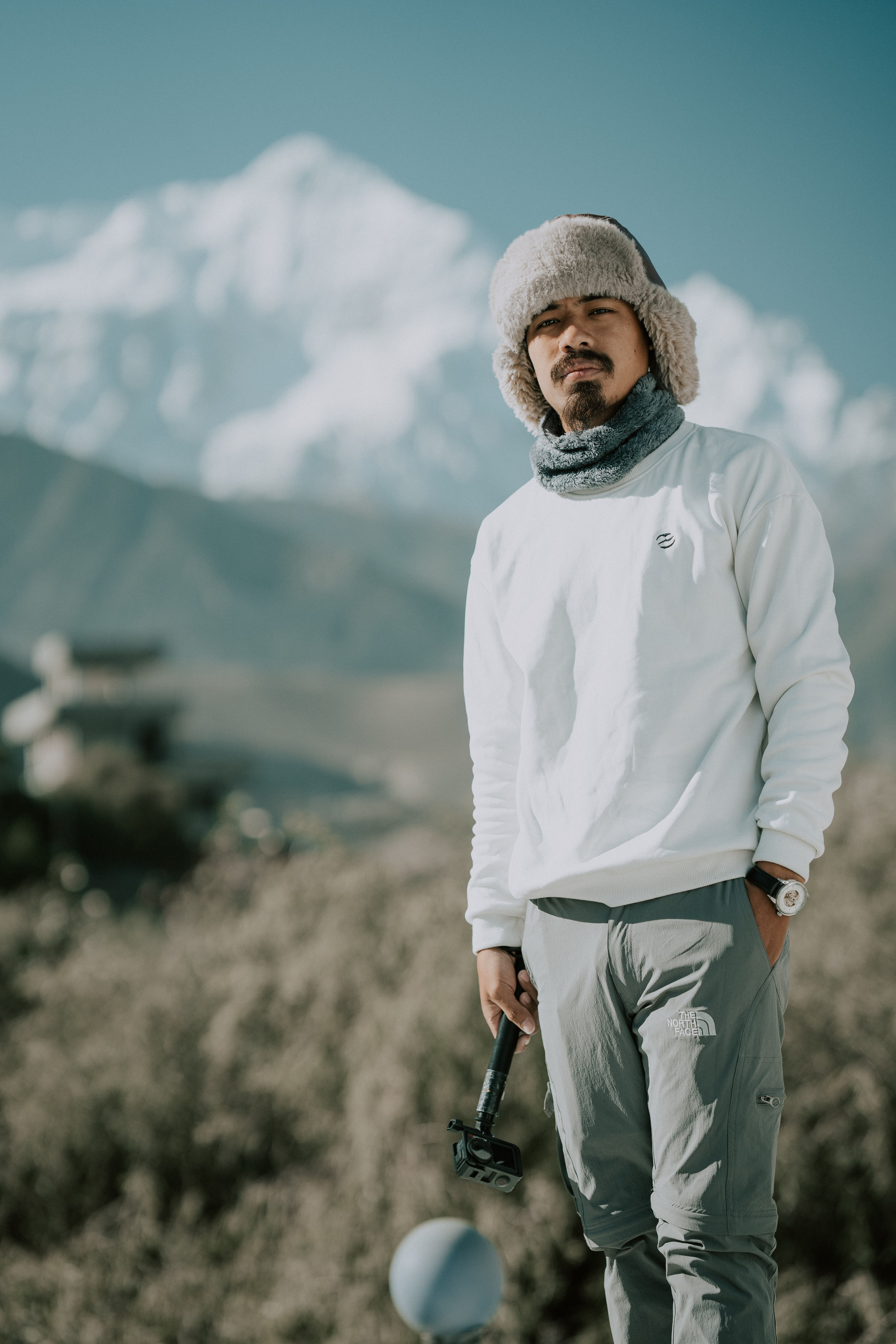 Man in winter clothing standing outdoors with snowy mountain in background.