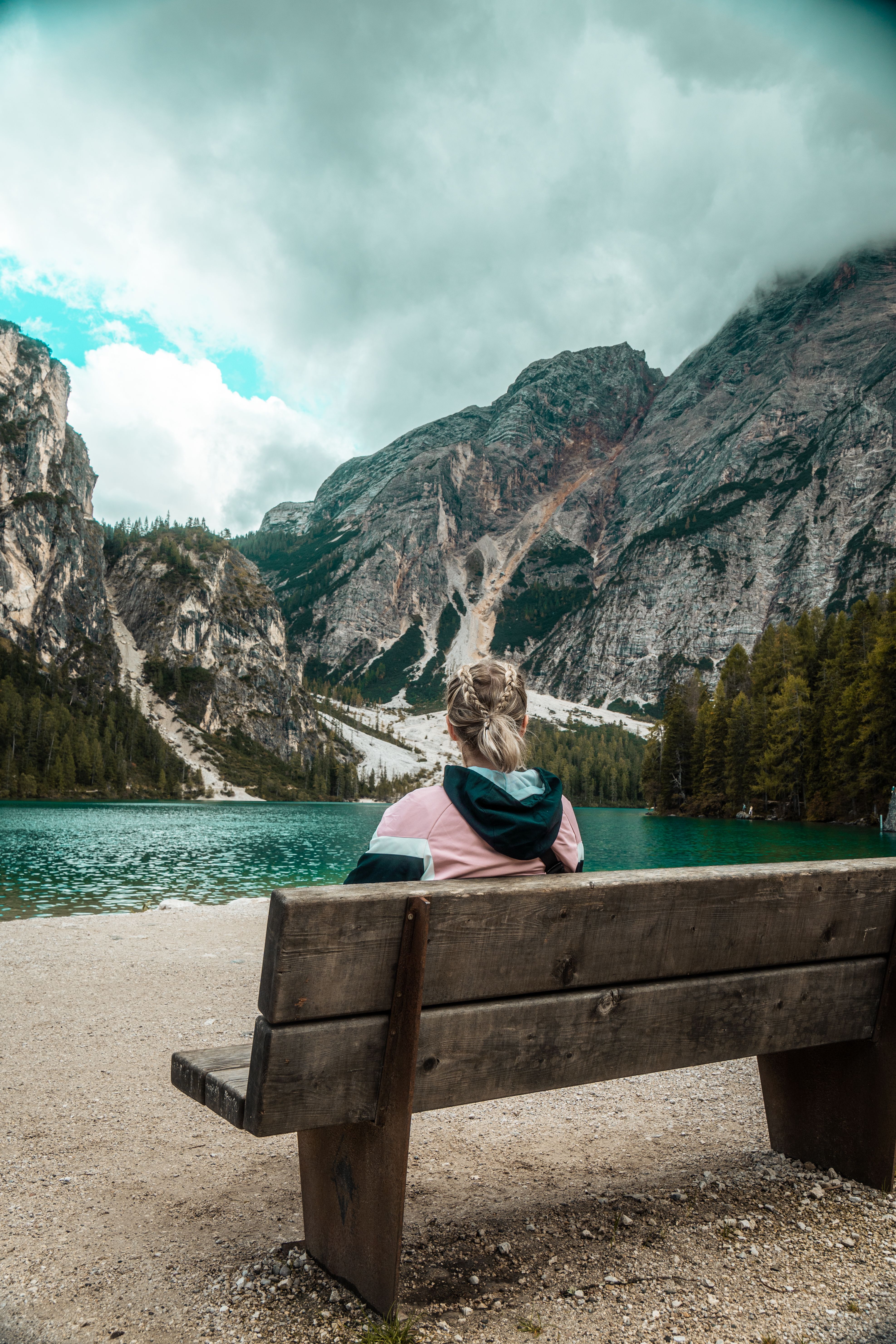 Woman Enjoying Mountain Lake View from Bench · Free Stock Photo