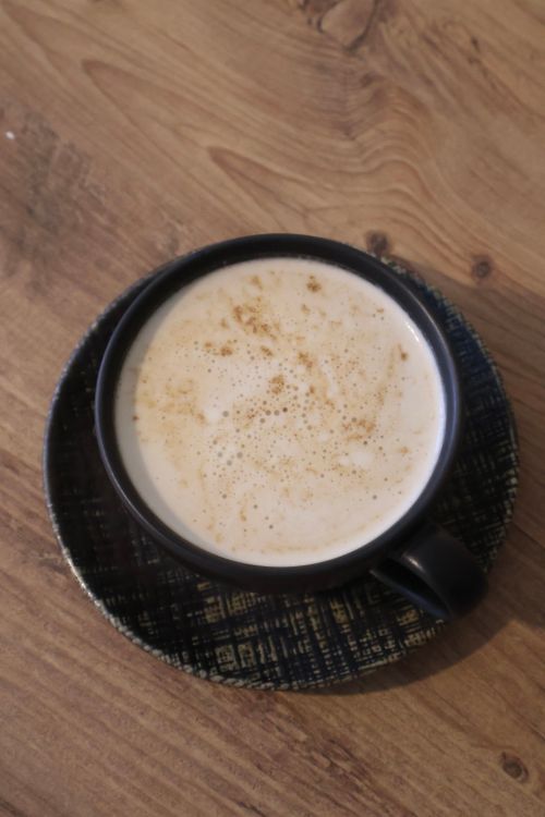 Free A creamy cappuccino served in a stylish black ceramic cup on a textured wooden table. Stock Photo