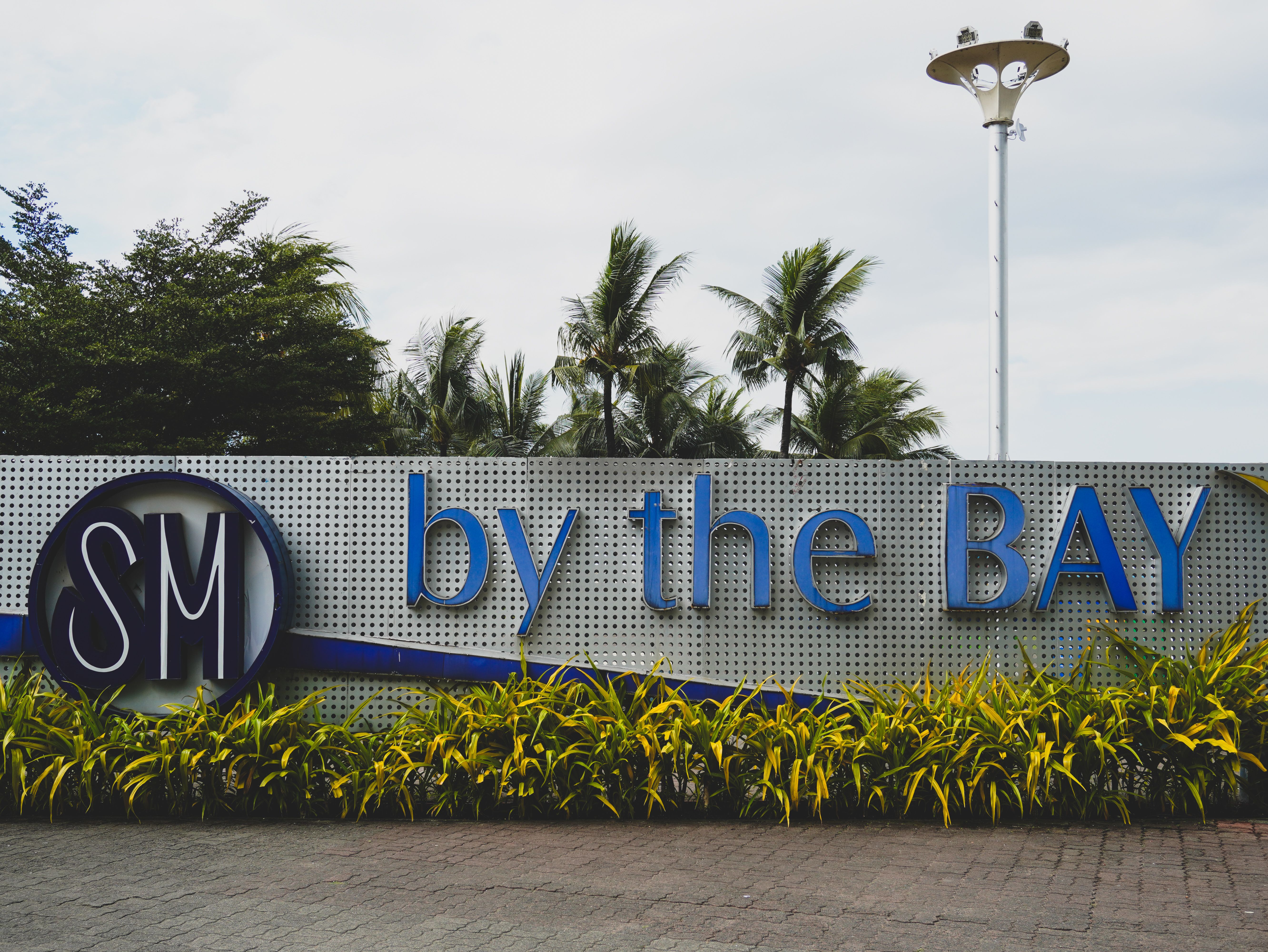 SM by the Bay Entrance Sign with Palm Trees · Free Stock Photo