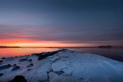 Stunning winter sunrise over icy coastline at Cove Island Park in Stamford, Connecticut.