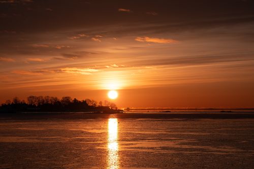 Free Capture of a beautiful winter sunrise over Stamford's coastline, with warm orange hues reflecting on tranquil waters. Stock Photo