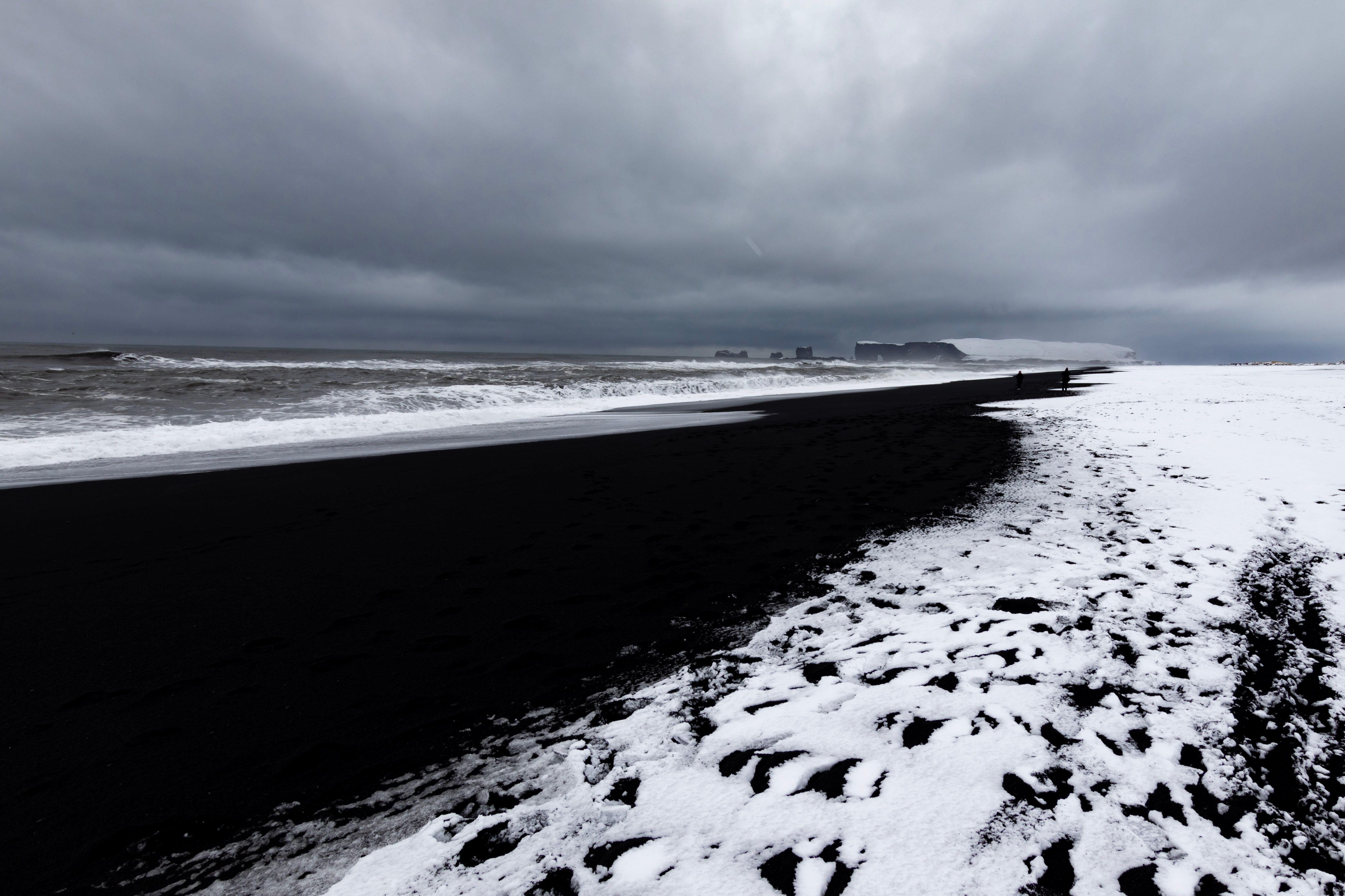 Stunning black sand beach with snow contrast under ominous clouds, captured in winter.. pexels, stunning, black