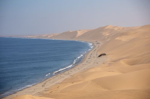 Free Majestic view of the Namib Desert's sand dunes meeting the Atlantic Ocean coastline in Namibia. Stock Photo
