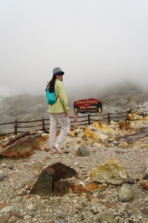 Free A traveler stands by the sign in a misty volcanic area in Indonesia, capturing an adventurous moment. Stock Photo