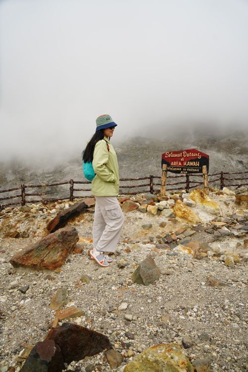 Free A woman in casual attire walking through a misty volcanic landscape, showcasing an adventurous spirit. Stock Photo