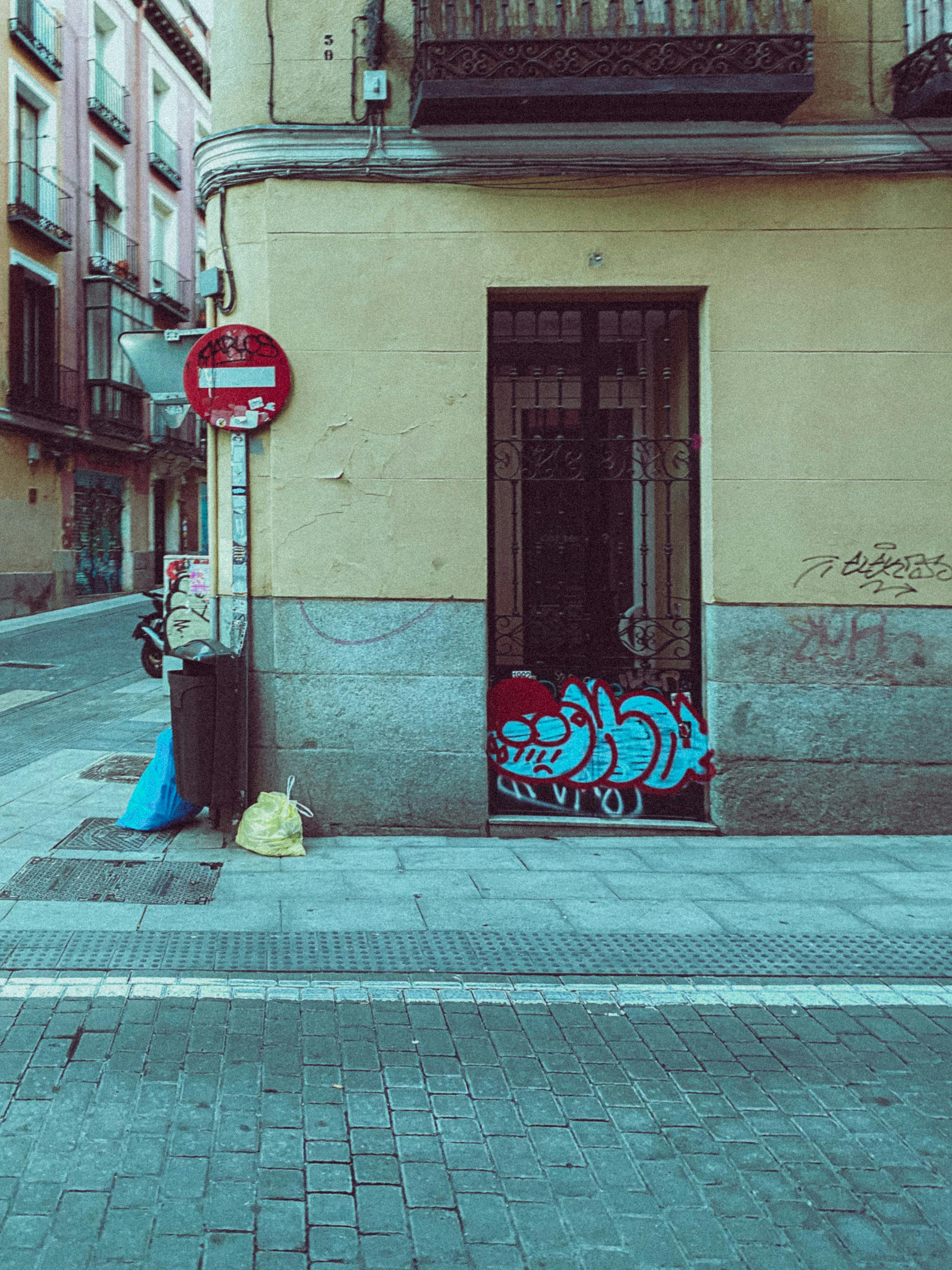 Ücretsiz Madrid'de, canlı grafitiler ve tarihi bir binanın önünde yer alan belirgin bir dur işaretiyle dikkat çeken kentsel sokak manzarası. Stok Fotoğraflar
