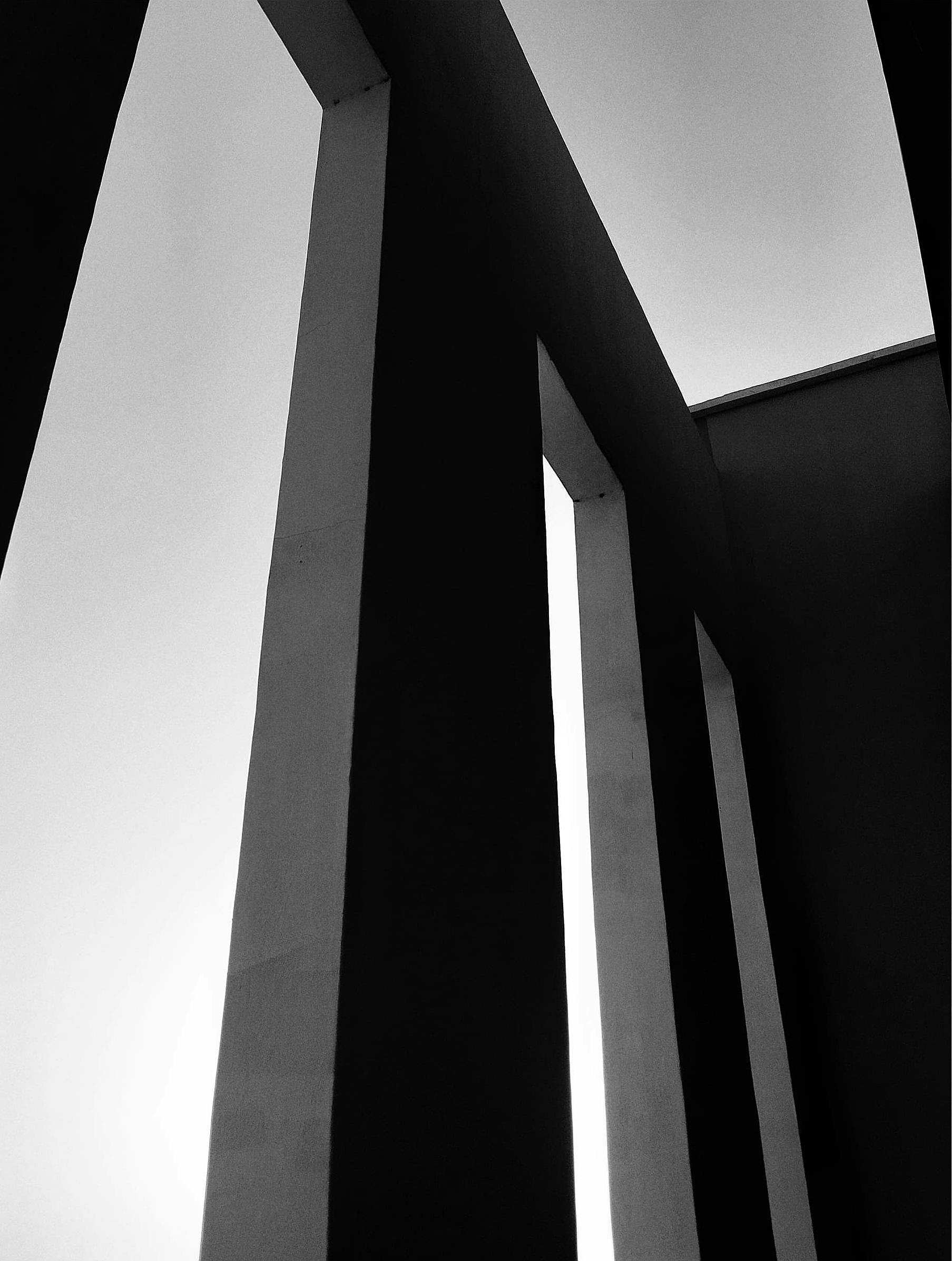 Bezpłatne Czarno-białe, abstrakcyjne zdjęcie wysokich kolumn architektonicznych tworzących geometryczne wzory. Zdjęcie z galerii