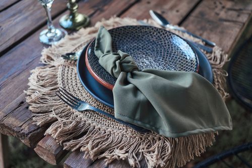 Free A rustic table setting featuring ceramic plates, woven placemats, and a green napkin for an elegant dining experience. Stock Photo