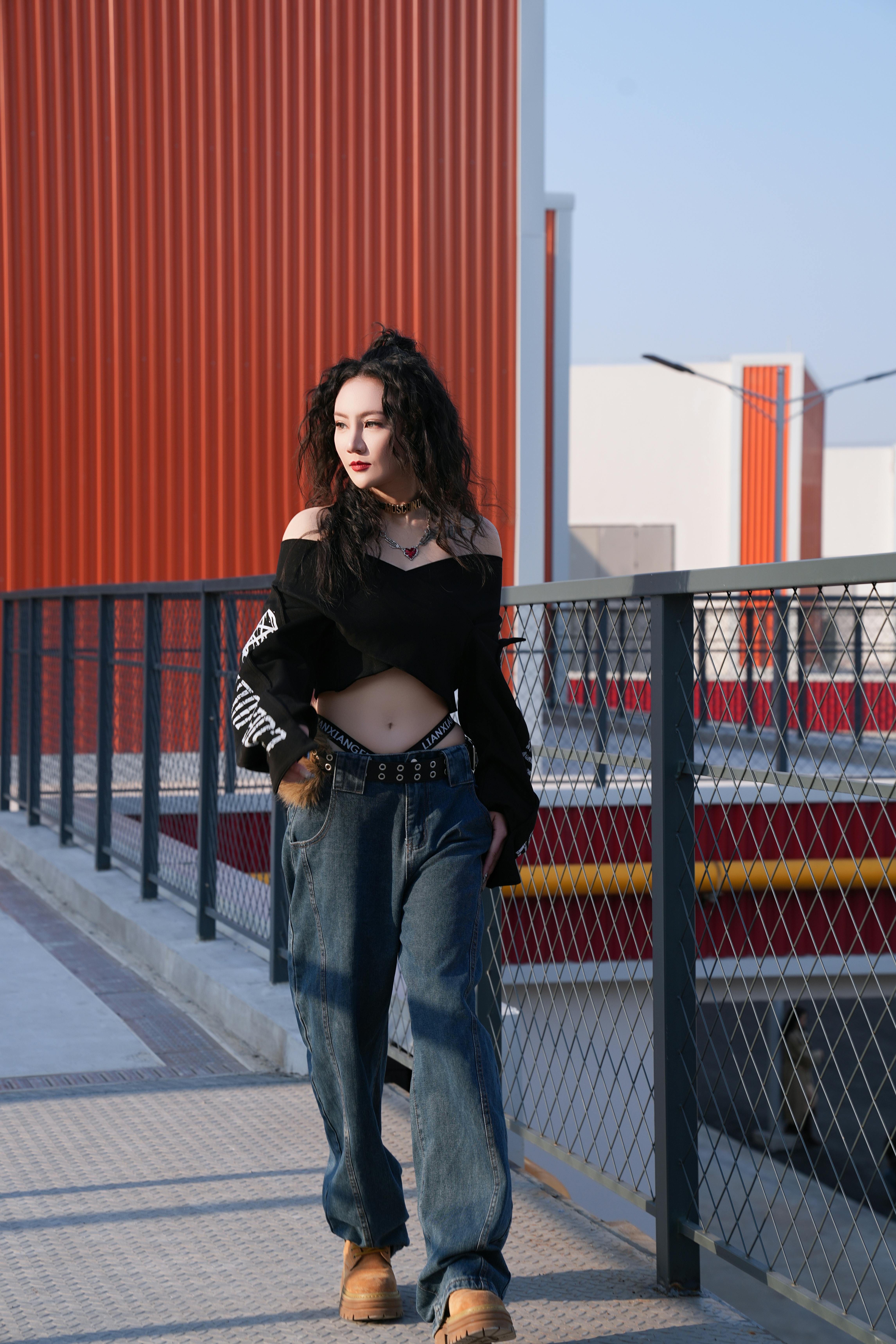 Fashionable young woman strolls confidently on a city walkway in cool chic attire.