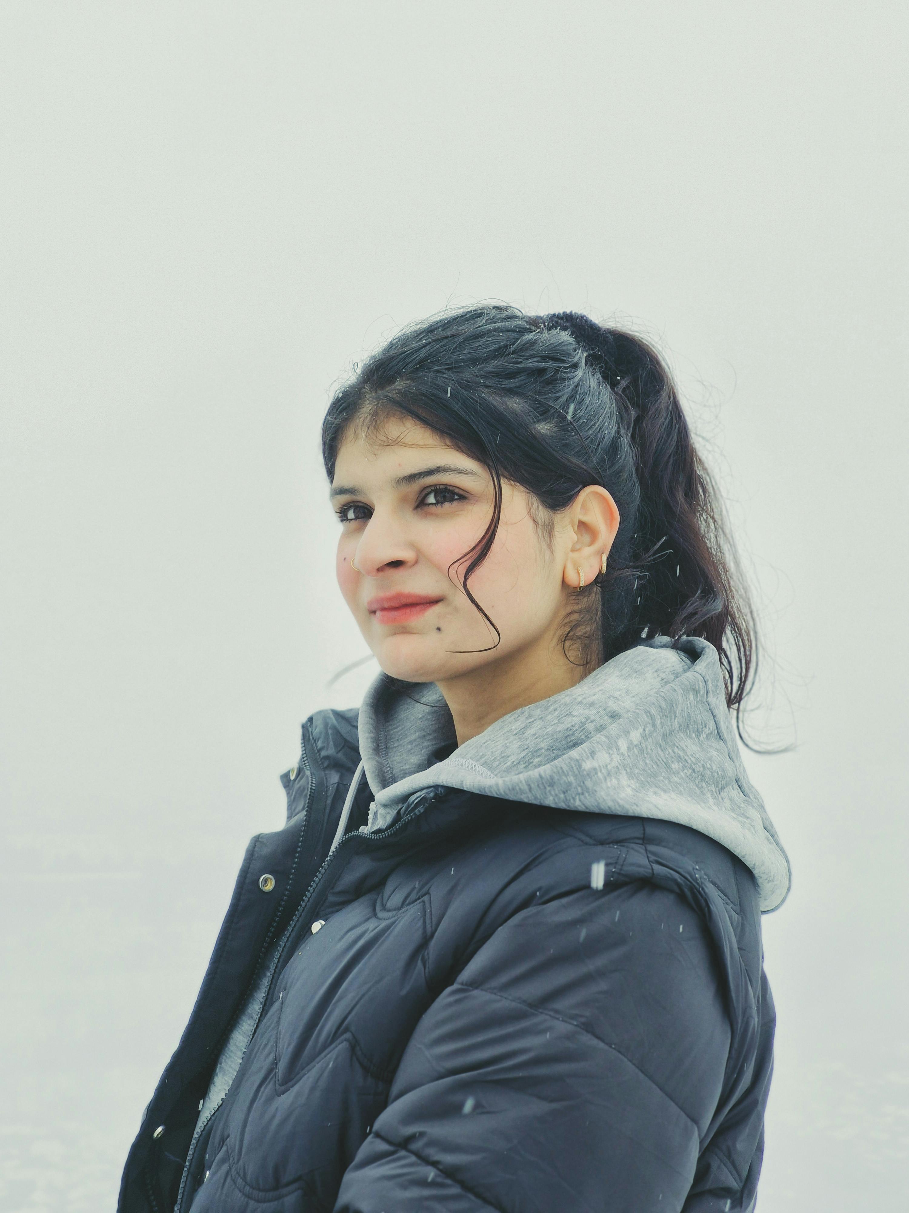 Portrait of a smiling woman in a winter jacket on a snowy day, outdoors.