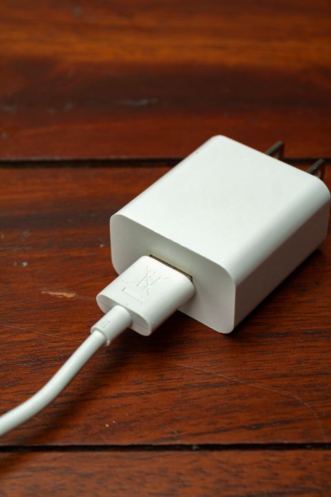 White USB-C charger with a cable on a wooden surface
