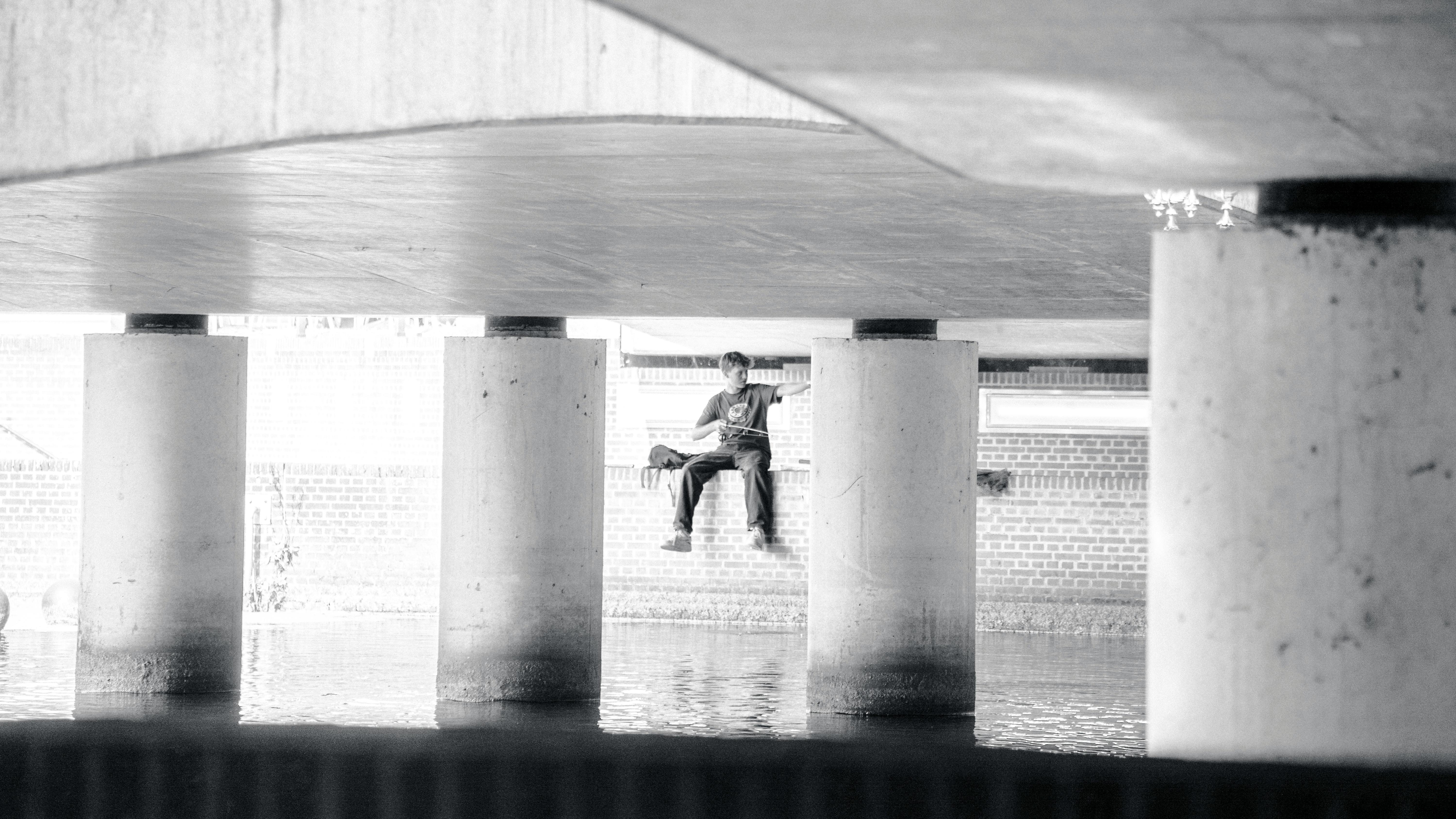 Gratis Una persona è seduta sotto un ponte sull'acqua ad Amersfoort, creando una serena scena urbana. Foto a disposizione