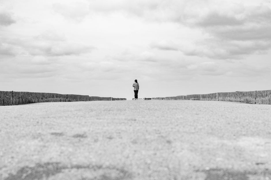 Black and white photo of a lone person on an empty road with a cloudy sky in Montevideo, Uruguay.