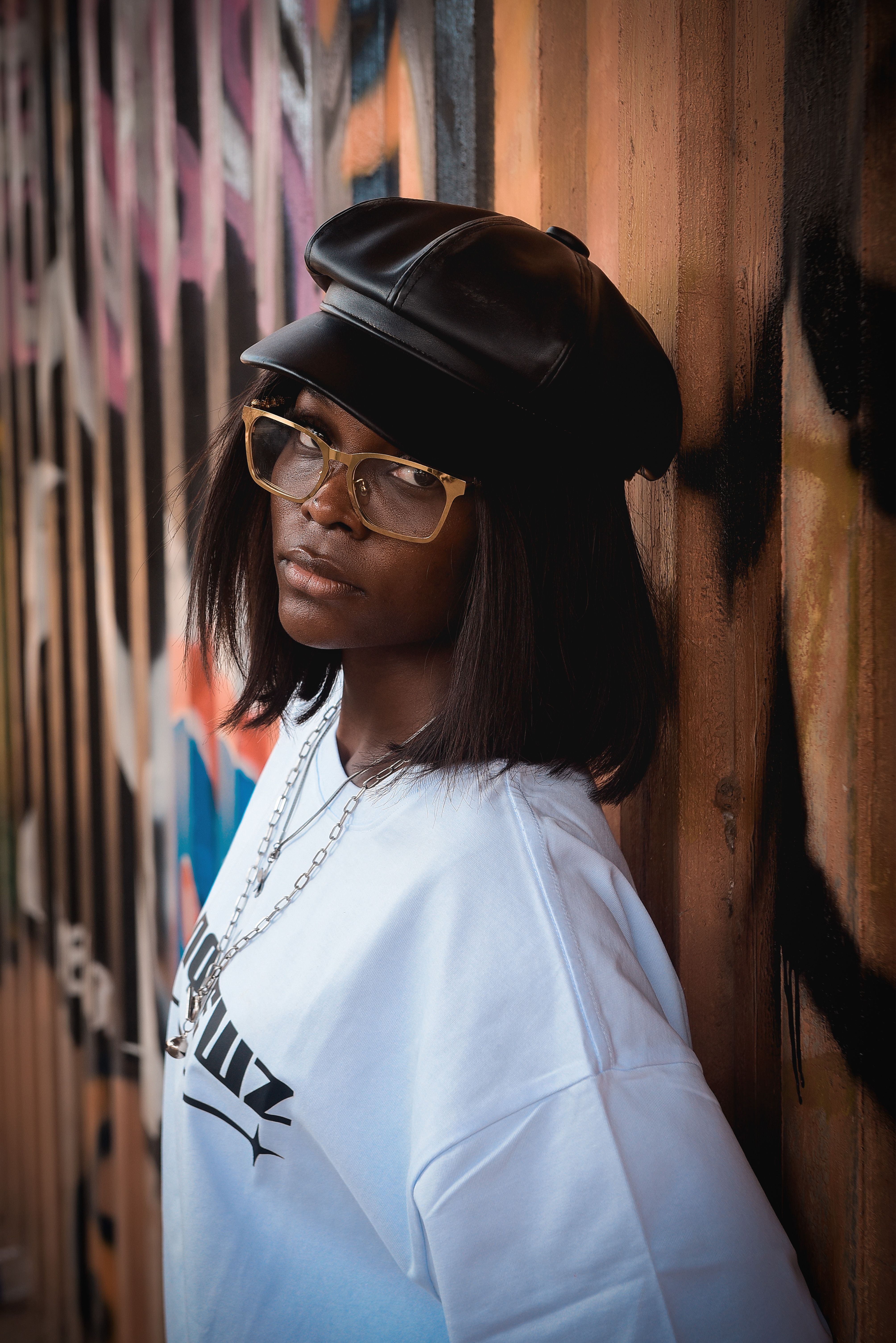 Young woman in trendy outfit posing against a colorful graffiti wall, exuding confidence.