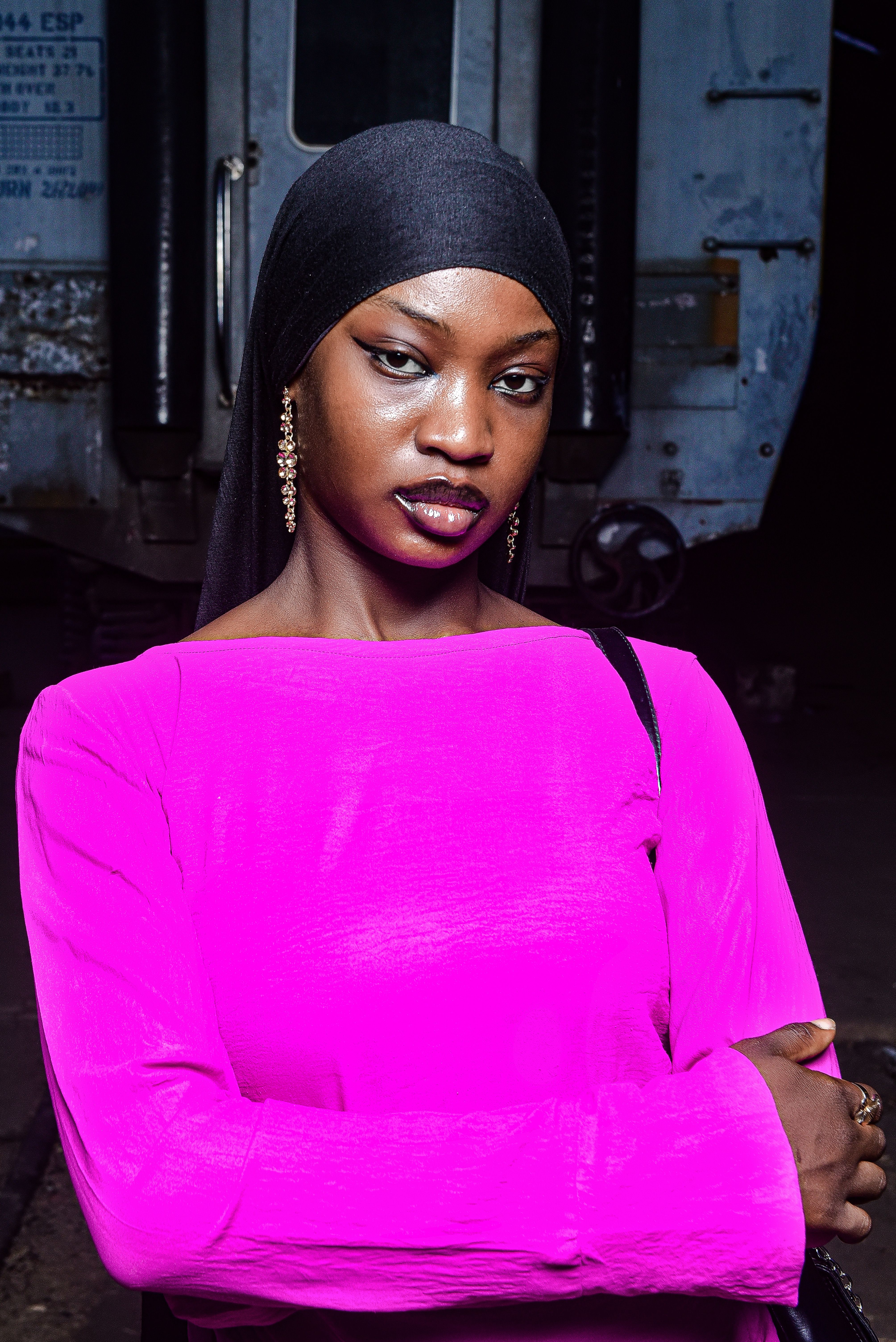 A stylish woman in a bright pink dress poses confidently, representing elegance and fashion.