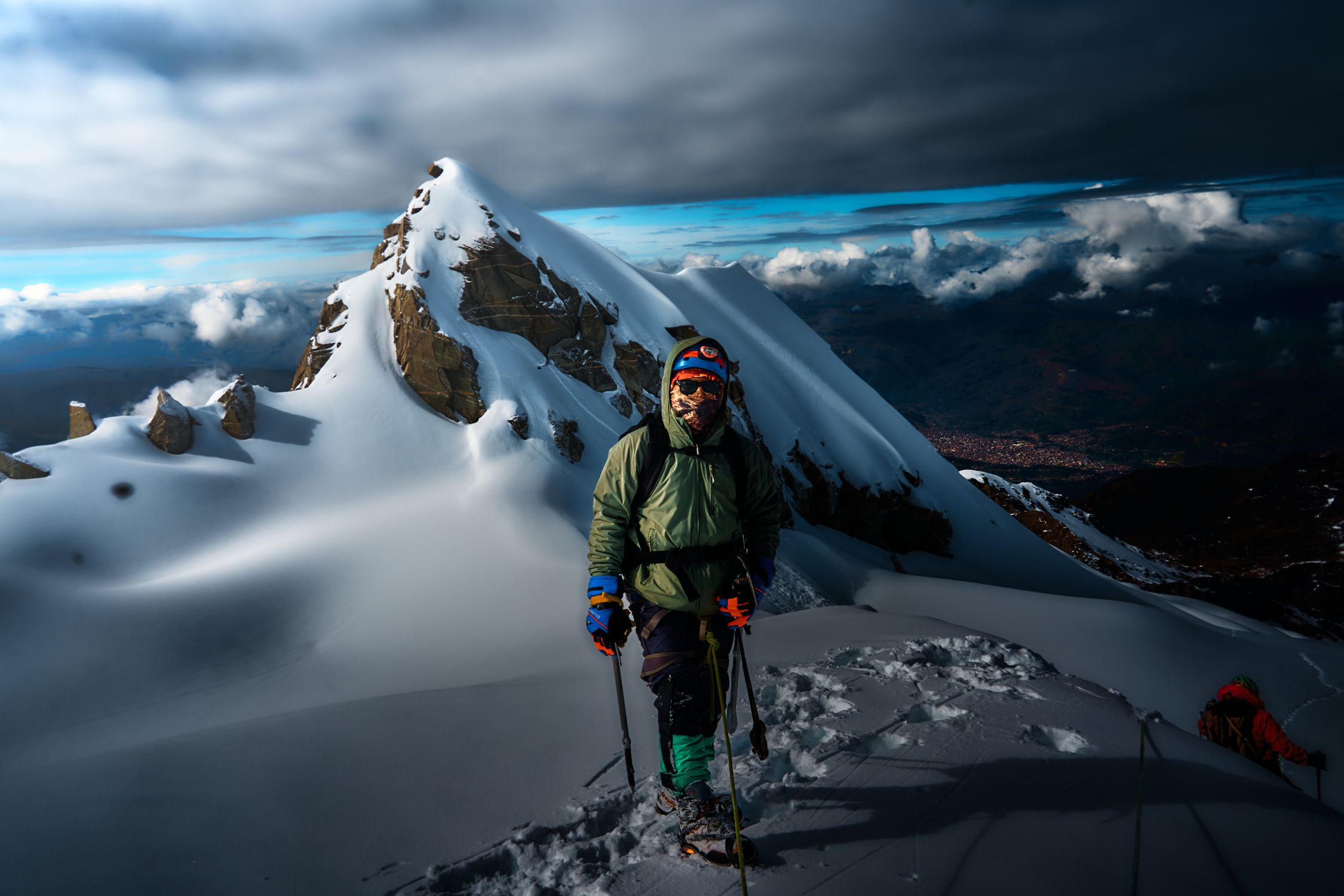 Climber in full mountaineering gear scaling an icy Andean peak near Huaraz, Peru against a dramatic sky