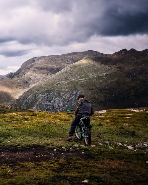 Free A lone biker explores the rugged landscape of Huaraz, Peru, under dramatic skies. Stock Photo