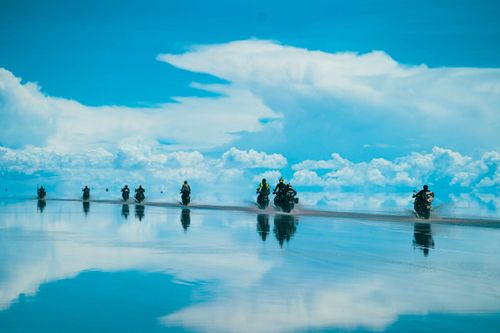 Free Breathtaking scene of motorcyclists cruising on reflective salt flats under a vast blue sky. Stock Photo