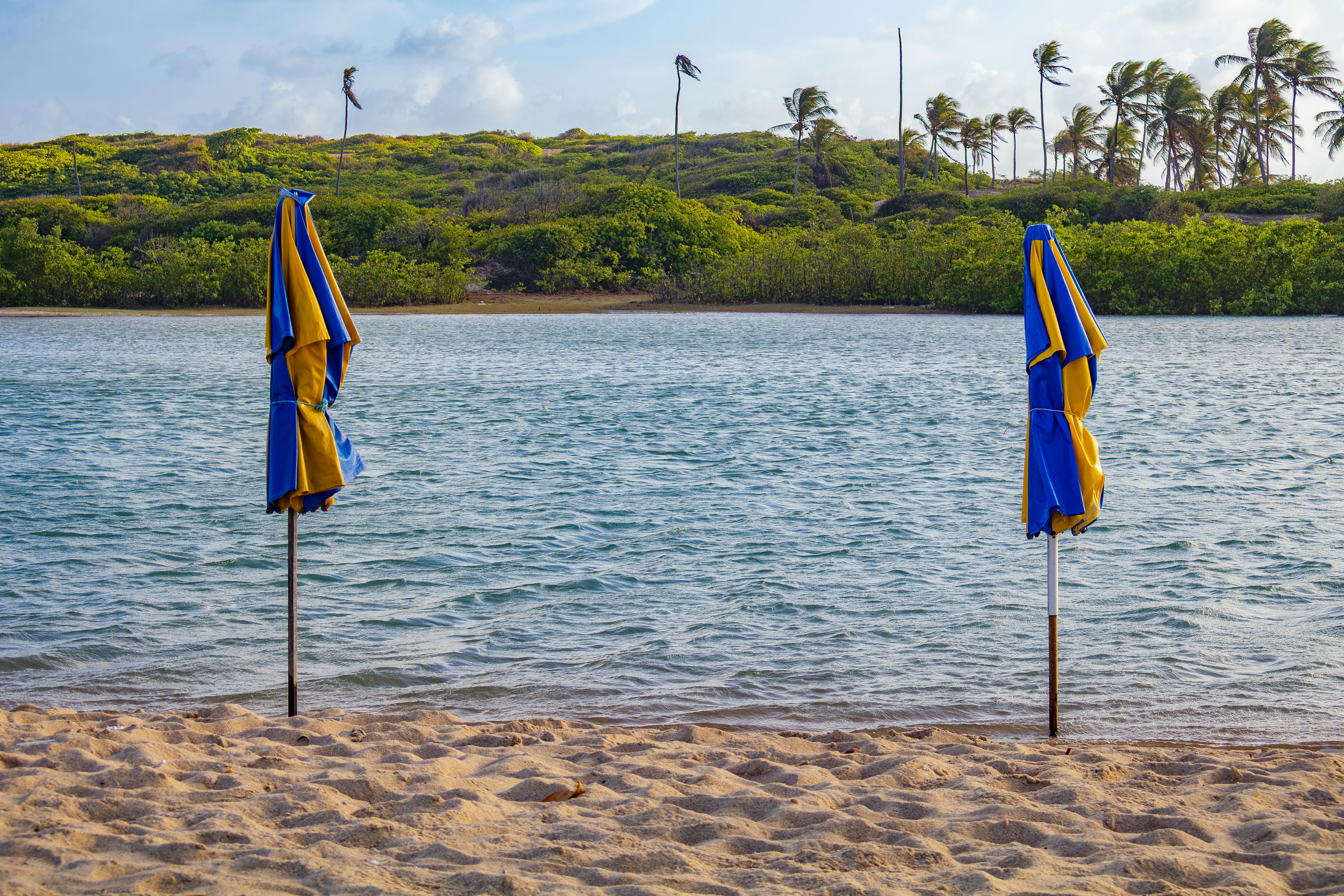 Serene tropical beach with two folded umbrellas by the shoreline in Maxaranguape.