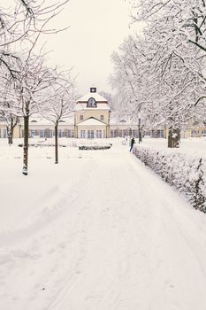 Serene winter scene of a snow-covered pathway leading to a historic building in Bad Hersfeld, Germany.