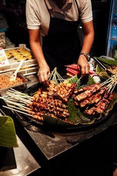 Street food vendor grilling meat skewers on a banana leaf at a vibrant night market in Manila.