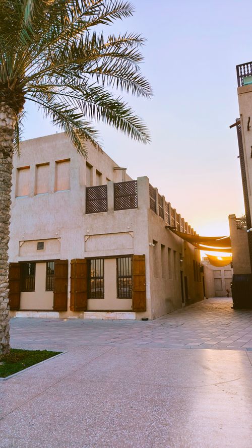 Free Scenic view of traditional Middle Eastern buildings with palm trees at sunset. Stock Photo