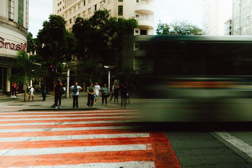 Free City street scene with people waiting at a crosswalk and a blurred bus passing by. Stock Photo