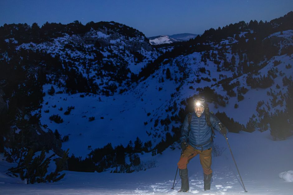A runner wearing a headlamp on a dark trail at night