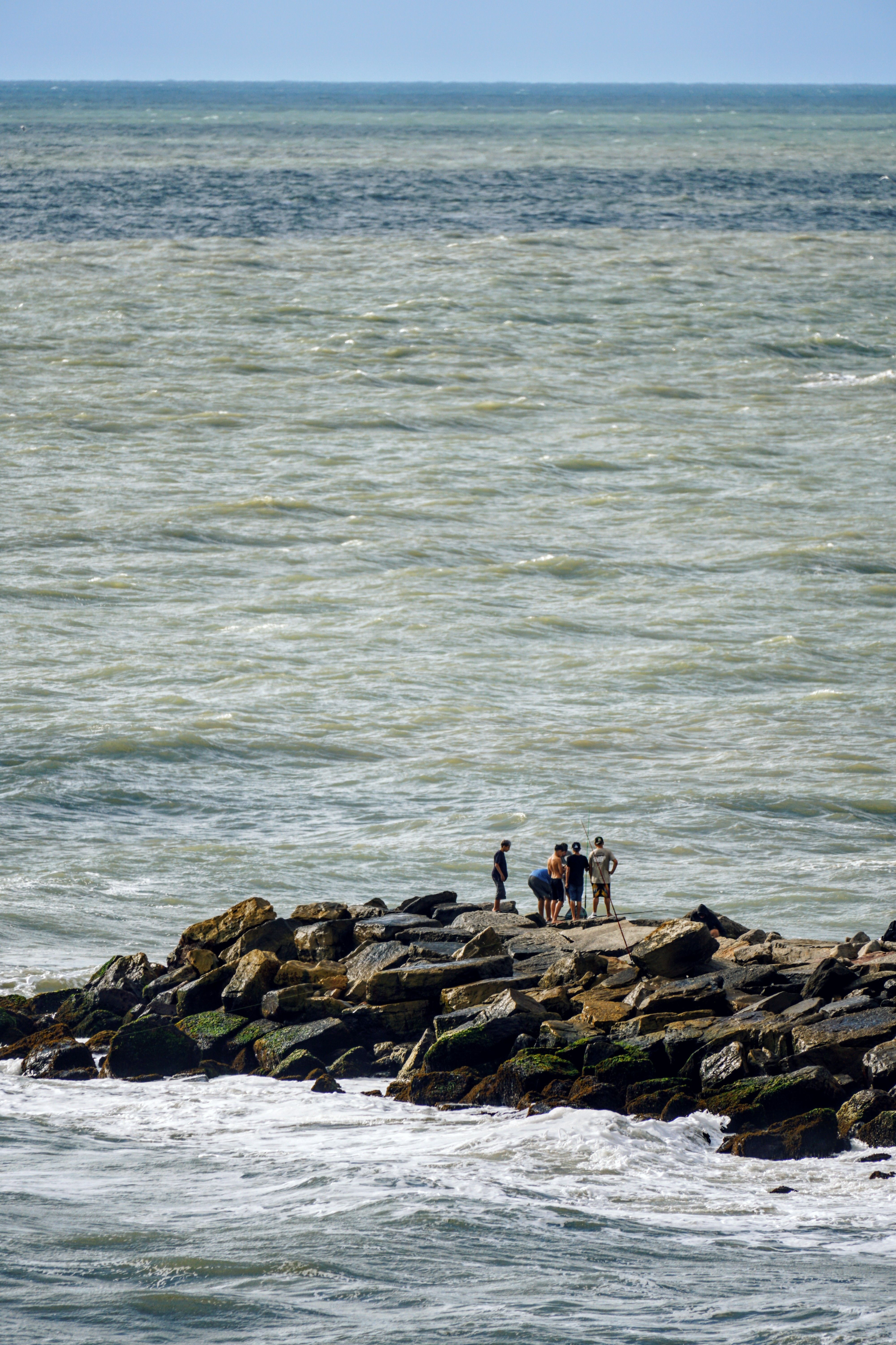 A group of people standing on a shoreline looking toward the sea.