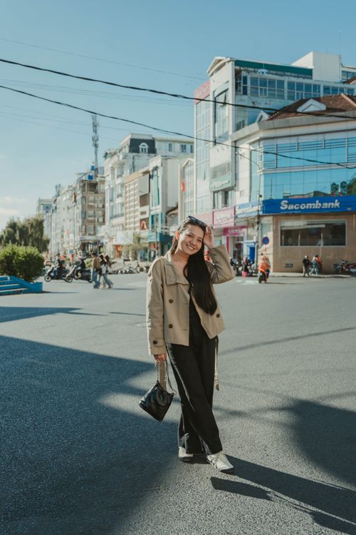 Free A young woman poses confidently on a sunny street in Dalat, Vietnam, exuding modern fashion and elegance. Stock Photo