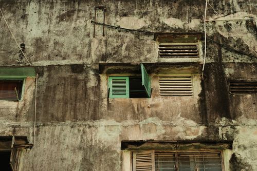 Free Rustic building facade with green shutters and aged walls, conveying urban decay. Stock Photo