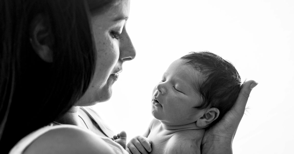 Black and white portrait of a mother lovingly holding her newborn.