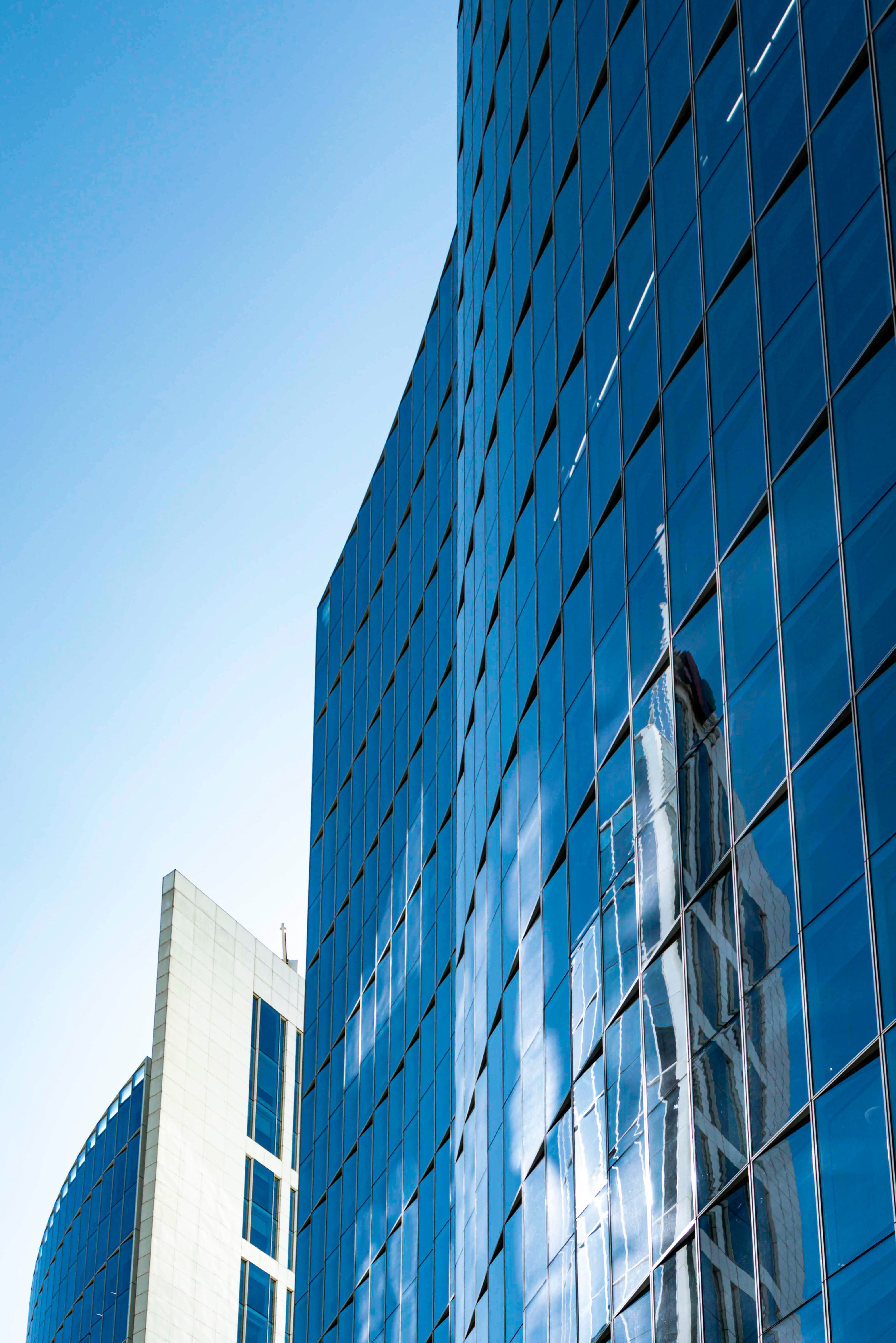 Curved blue glass skyscrapers reflecting clouds and sky, symbolizing modern architecture in Argentina.