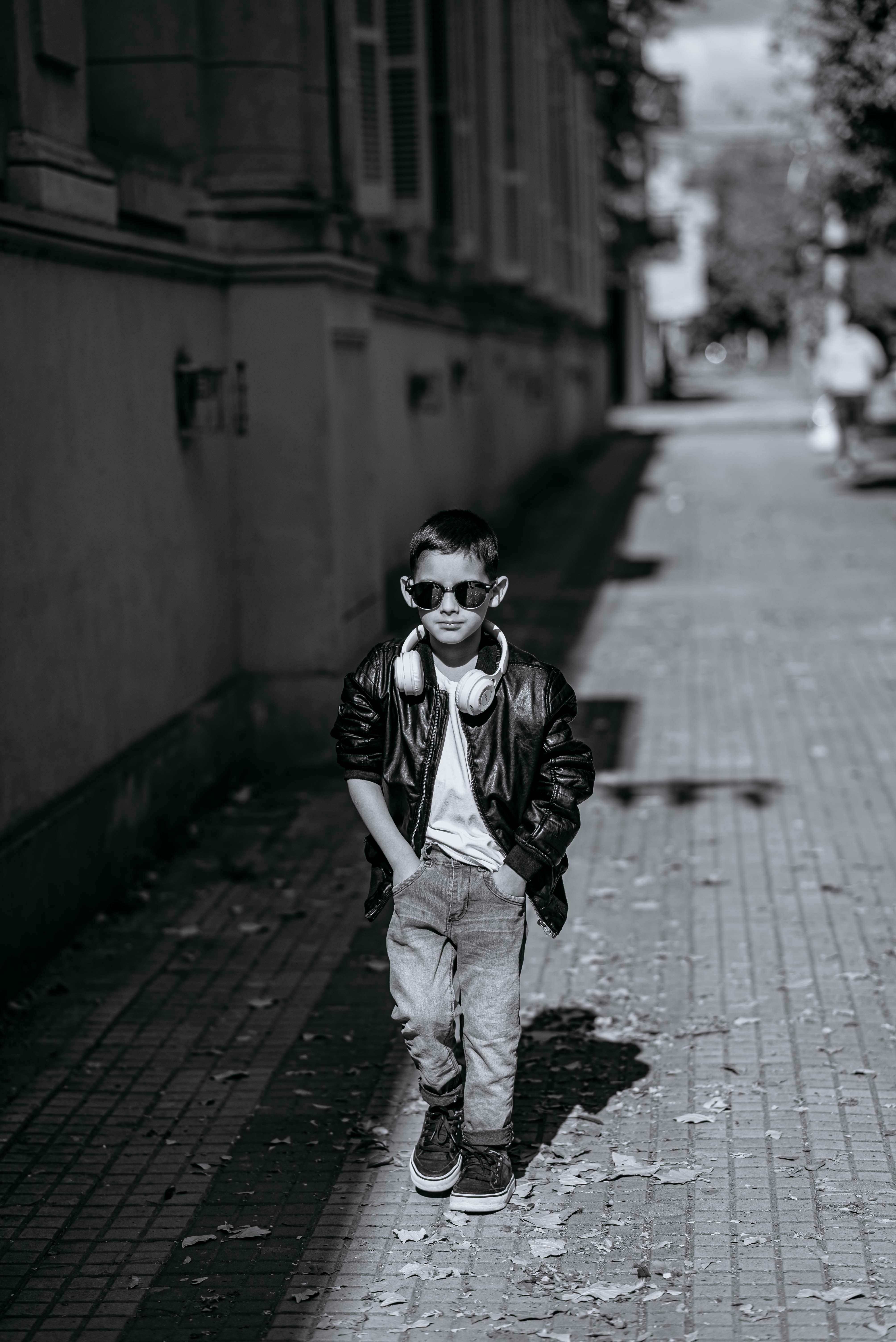 ingyenes Fekete-fehér fotó egy vagány fiatal fiúról, aki napszemüvegben és fejhallgatóval sétál egy argentin városi utcán. Stockfotó