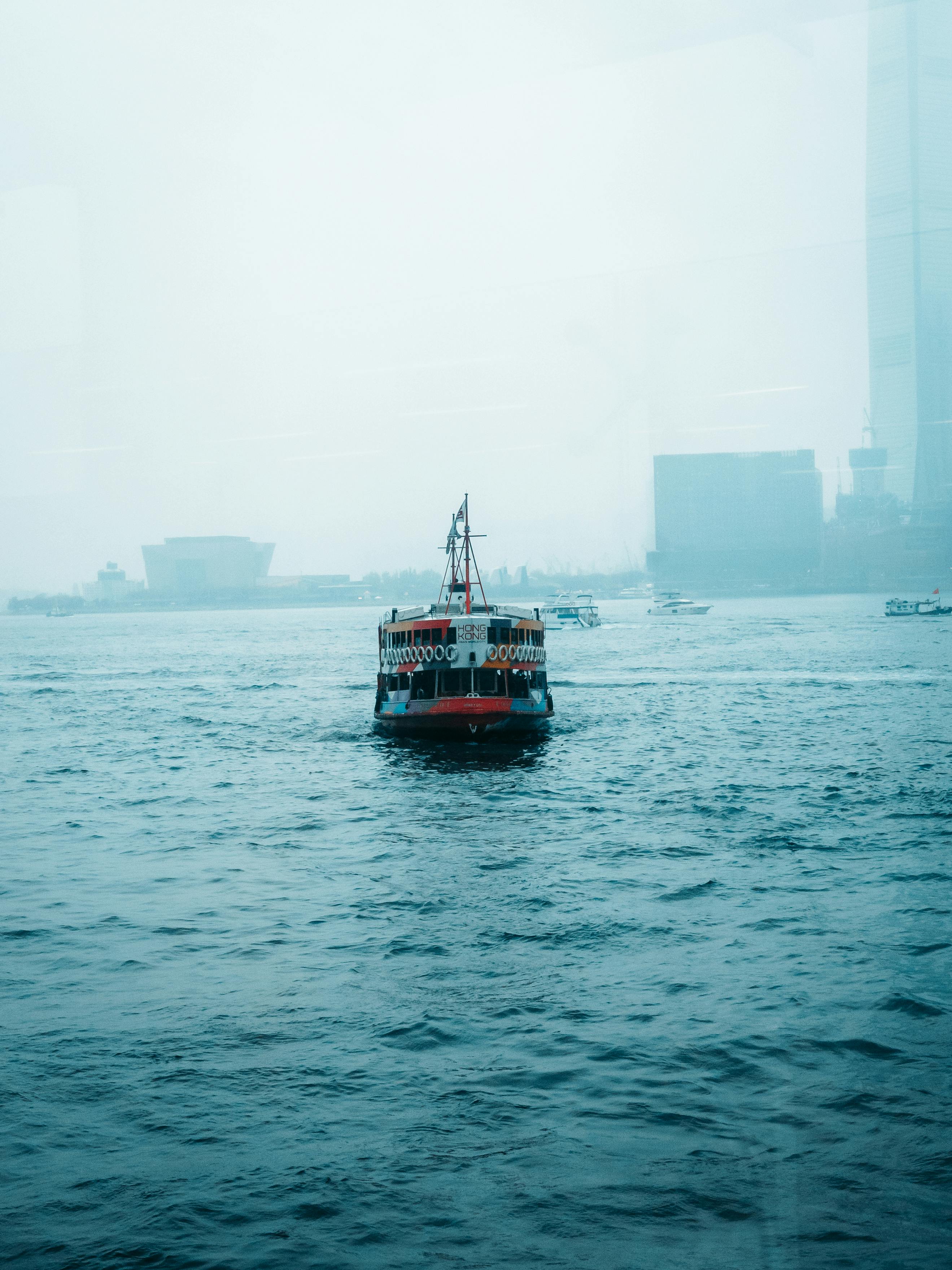 Δωρεάν Ένα πολύχρωμο φέρι διασχίζει το λιμάνι του Χονγκ Κονγκ σε μια ομιχλώδη ατμόσφαιρα, αναδεικνύοντας τη γοητεία της αστικής παραλίας. Φωτογραφία από στοκ φωτογραφιών