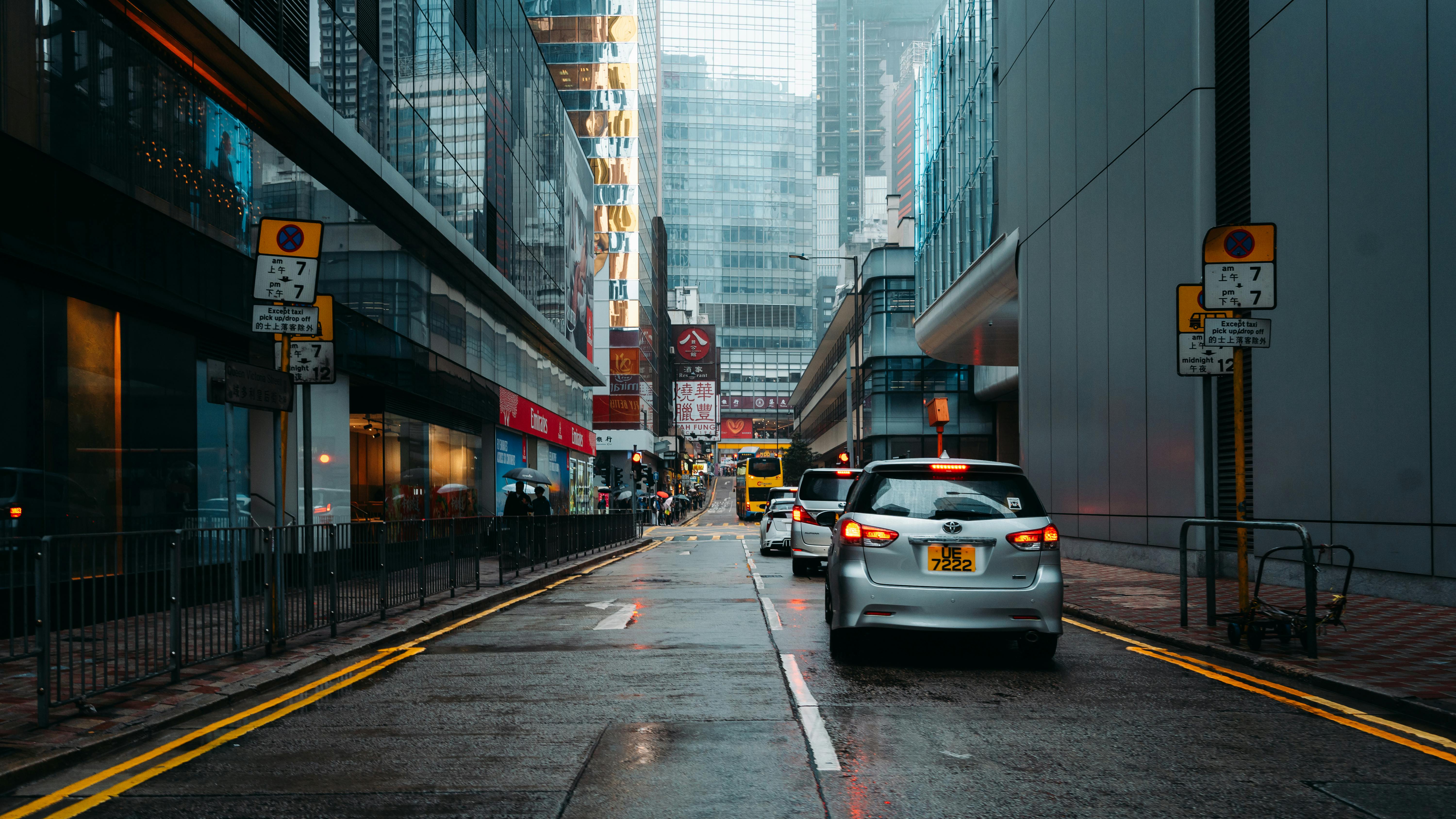 grátis Rua urbana chuvosa com carros, prédios altos e pavimento molhado e reluzente. Foto profissional