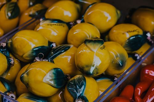Free Vibrant yellow ceramic lemons artfully displayed in market setting, capturing artistic craftsmanship. Stock Photo